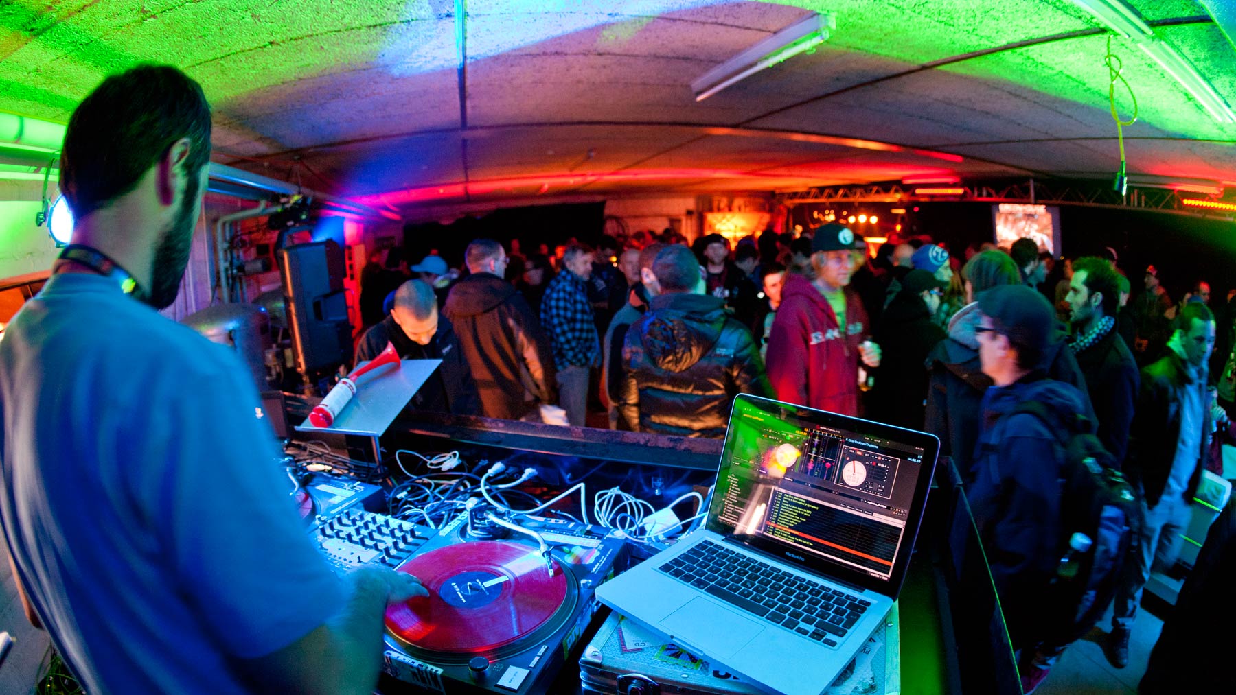 DJ vor tanzendem Publikum im Schweinwerferlicht